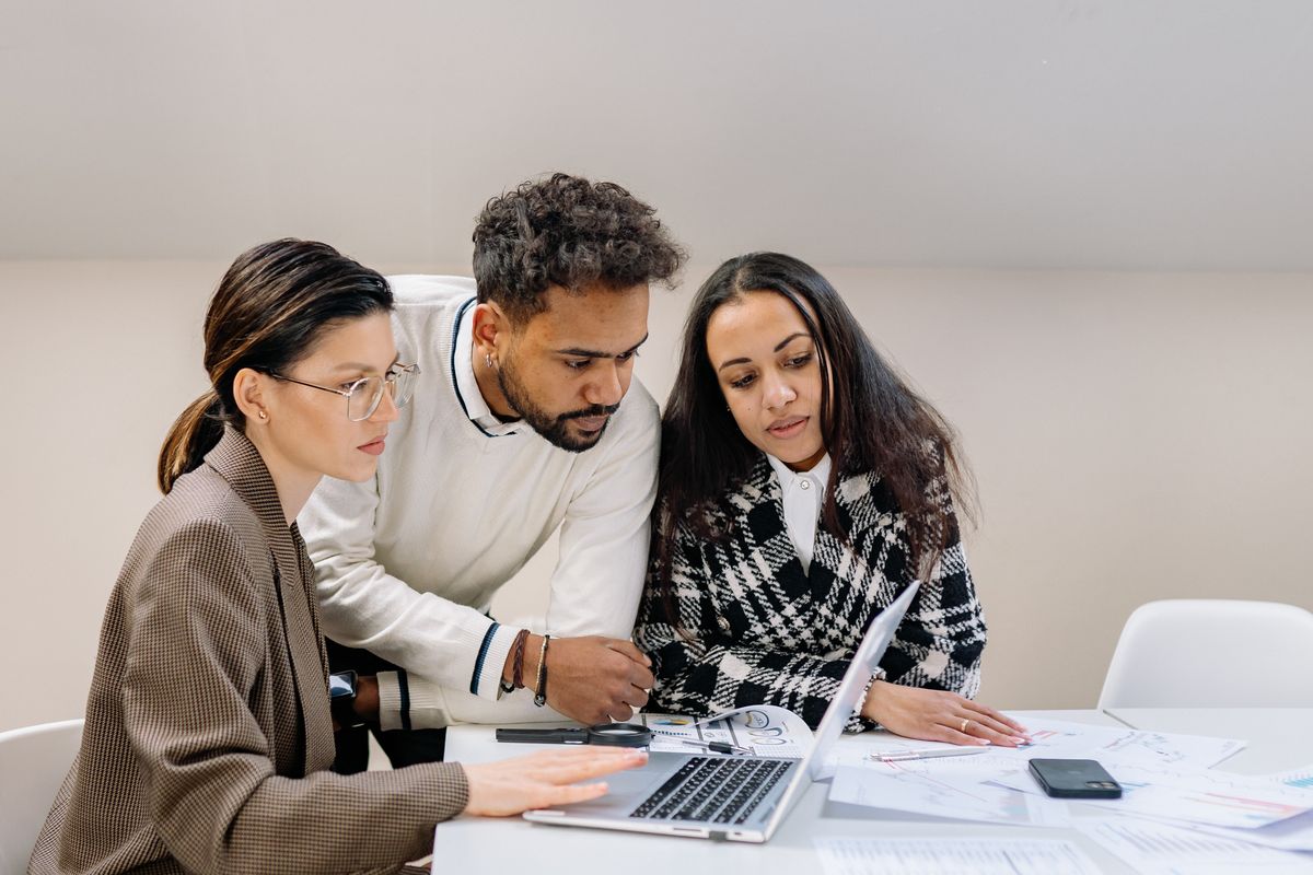 Three colleagues planning work around a laptop